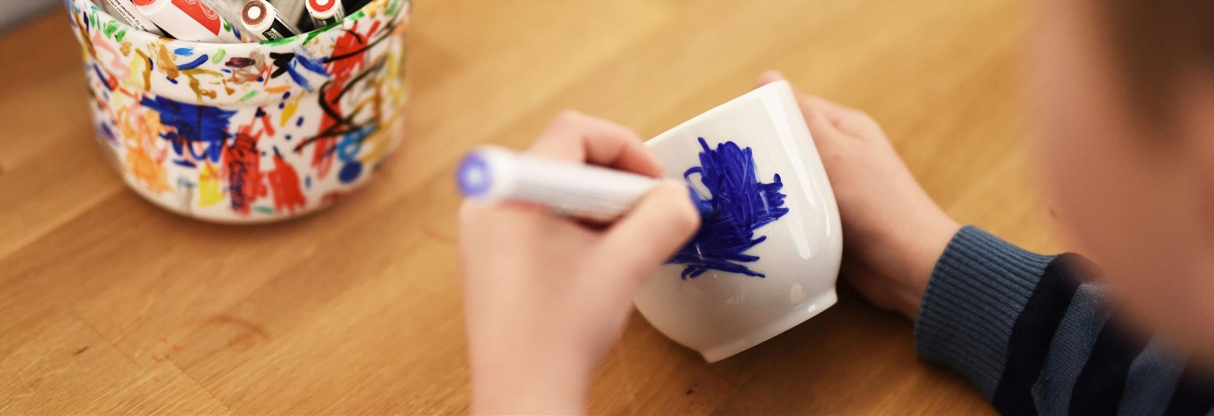 child paints on a cup