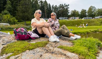 2 women are sitting on a rocky shore at Dikkon bathing area on Sandøya in Porsgrunn
