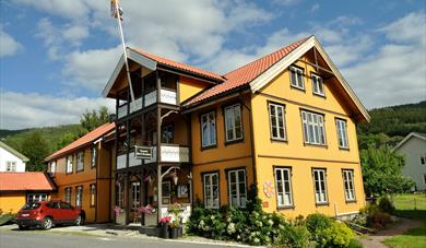Fyresdal Bed and Breakfast on a sunny day. Flowers around the yellow house. 