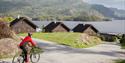 The cyclist rides past cabins.