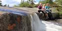 group of young people sitting by a small waterfall